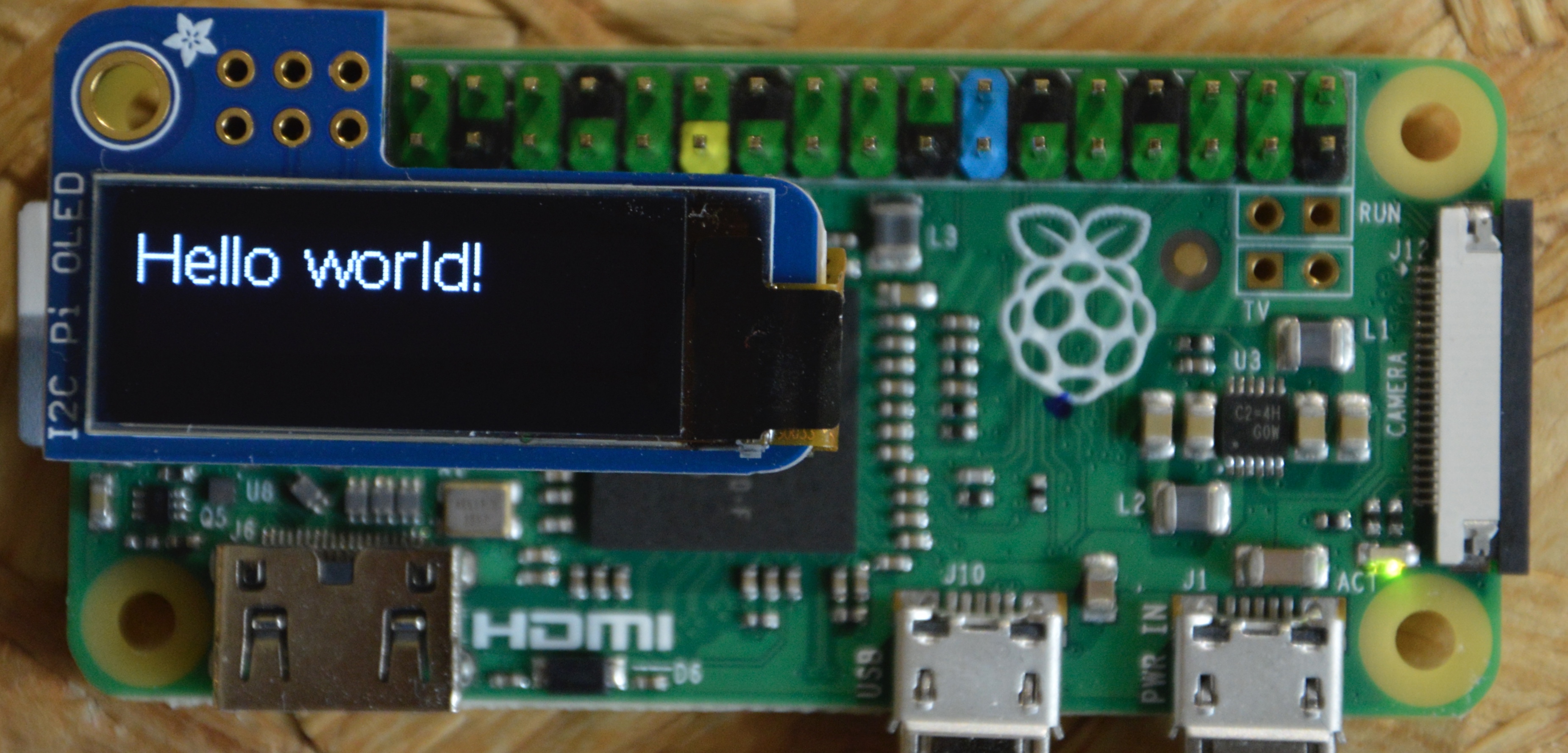 Image of Raspberry Pi with PiOLED connected to it on which "Hello world!" is visible